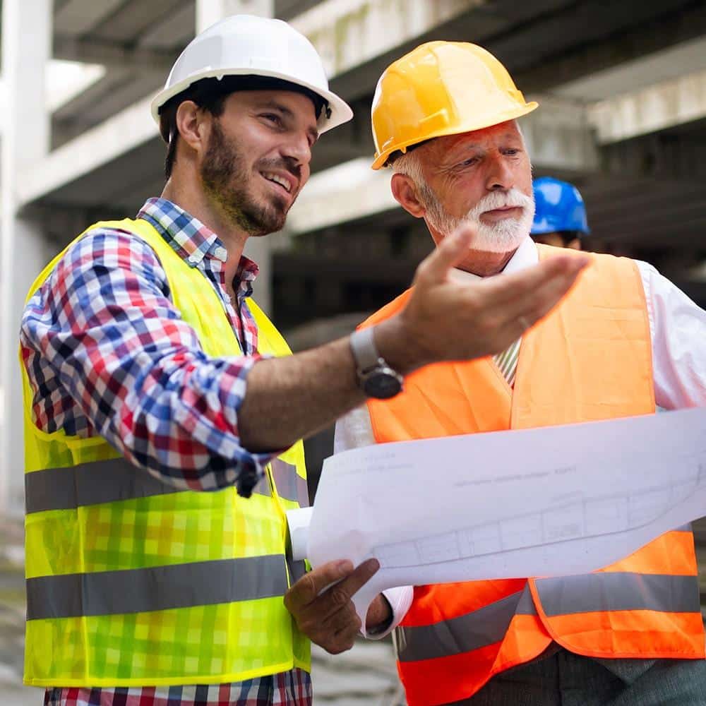 Two men in hard hats talking to each other.