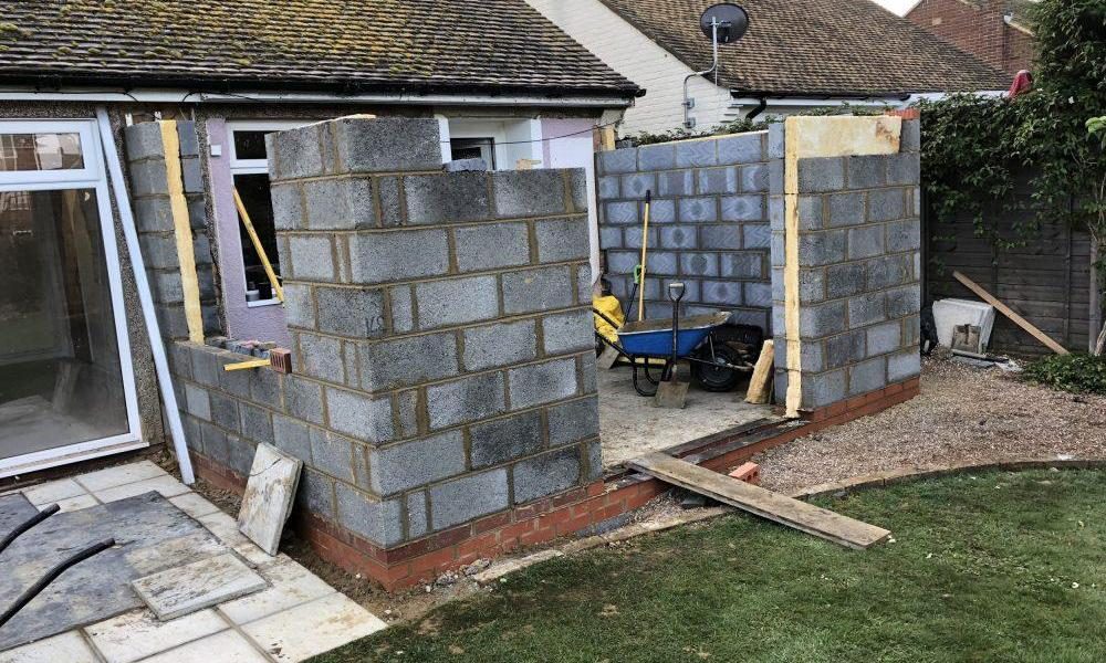 A house under construction with a brick wall.